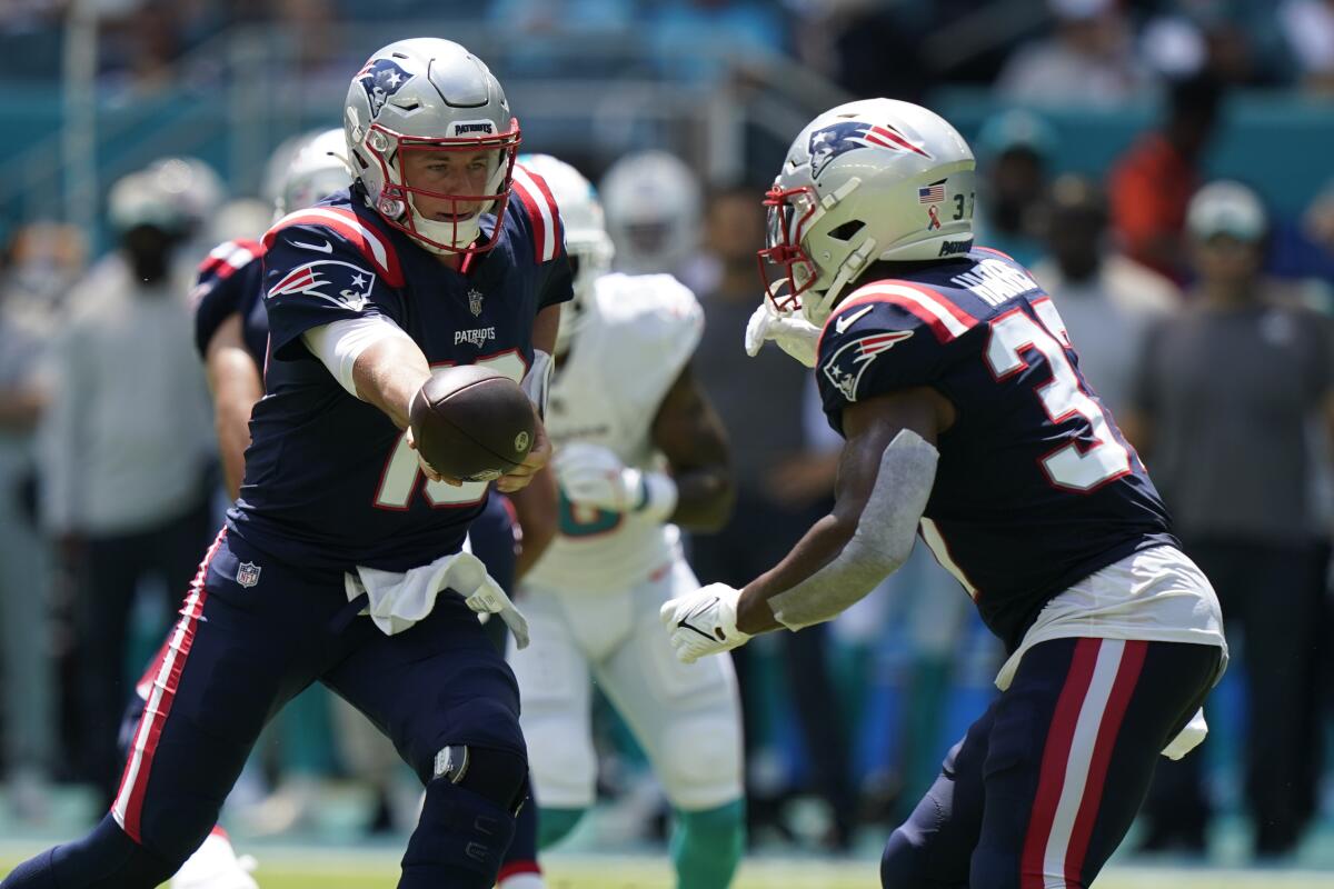 New England Patriots quarterback Mac Jones (10) hands the ball to running back Damien Harris (37) during the first half of an NFL football game against the Miami Dolphins, Sunday, Sept. 11, 2022, in Miami Gardens, Fla. (AP Photo/Lynne Sladky)
