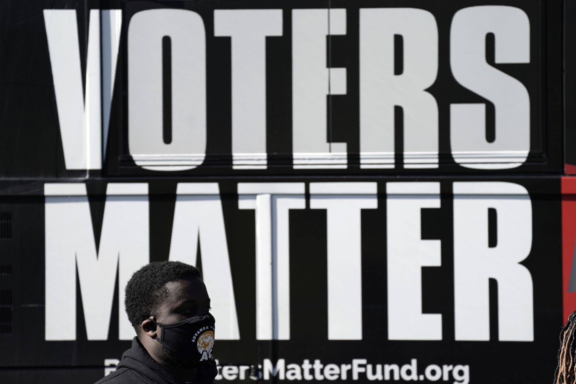 A man wearing a mask encourages Black people to vote at the Graham Civic Center polling site in Graham, N.C., on Tuesday.
