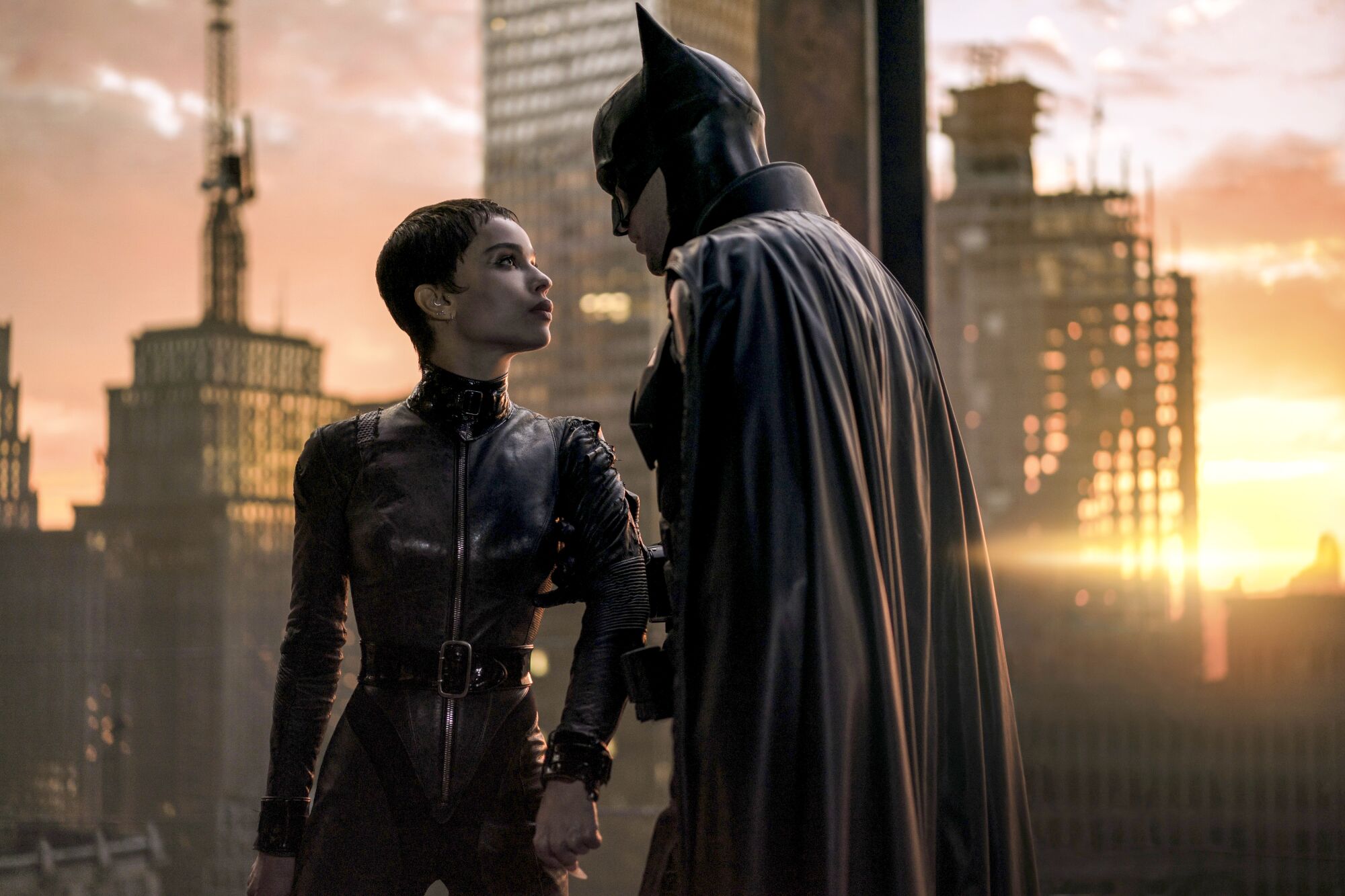 Batman and Catwoman look at each other, with a cityscape backdrop 