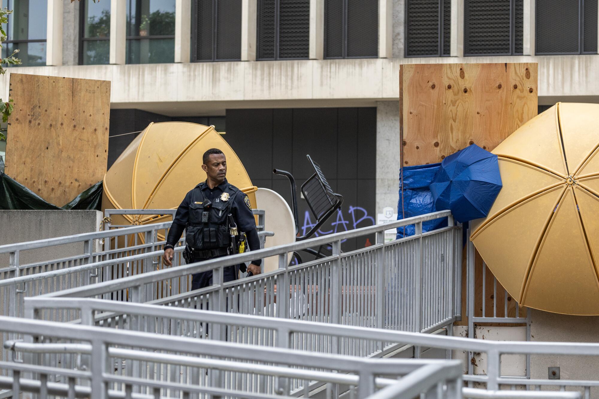 A police officer walks past an opening in barricades surrounding the student services building at Cal State L.A.