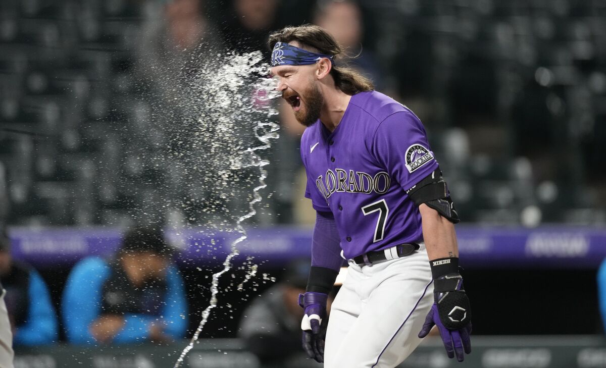 Colorado Rockies' Brendan Rodgers is hit by a stream of water from a teammate as he circles the bases after hitting a two-run home run off Miami Marlins relief pitcher Cole Sulser during the 10th inning of the second game of a baseball doubleheader Wednesday, June 1, 2022, in Denver. (AP Photo/David Zalubowski)
