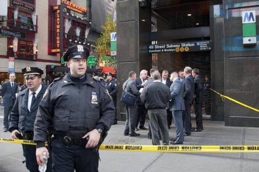 Uniformed and plainclothes police officers gather outside the subway station in New York where witnesses say a man was killed after being pushed onto the tracks. A suspect has been picked up for questioning.