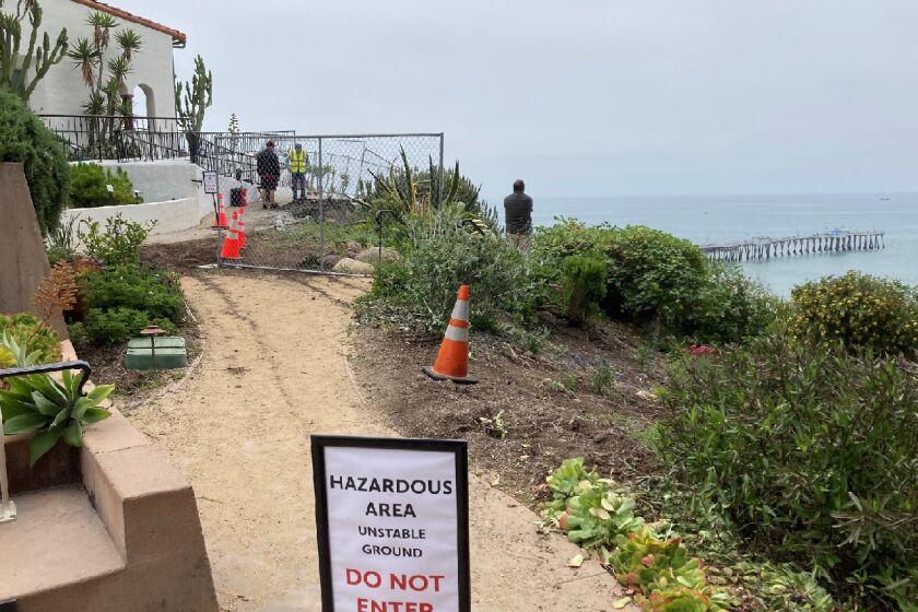 Local officials examine a landslide Friday at Casa Romantica in San Clemente
