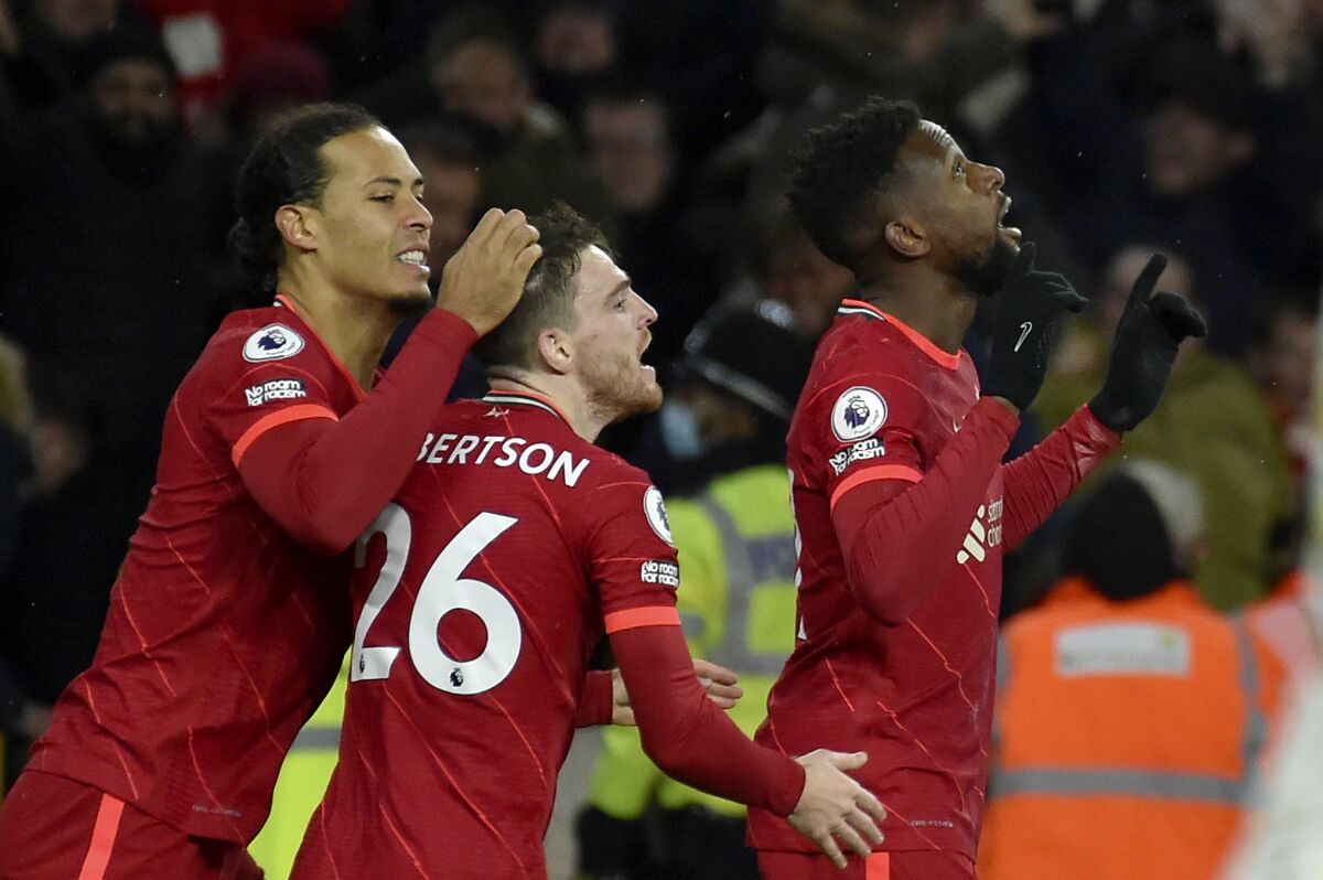 Liverpool's Virgil van Dijk, left, and Andrew Robertson celebrate after Divock Origi, right, scored the opening goal during the English Premier League soccer match between Wolverhampton Wanderers and Liverpool at the Molineux Stadium in Wolverhampton, England, Saturday, Dec. 4, 2021. (AP Photo/Rui Vieira)