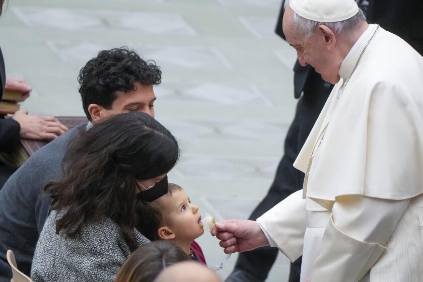 Pope Francis takes the pacifier of a baby during his weekly general audience in the Paul VI Hall at the Vatican, Wednesday, Feb. 23, 2022. (AP Photo/Gregorio Borgia)