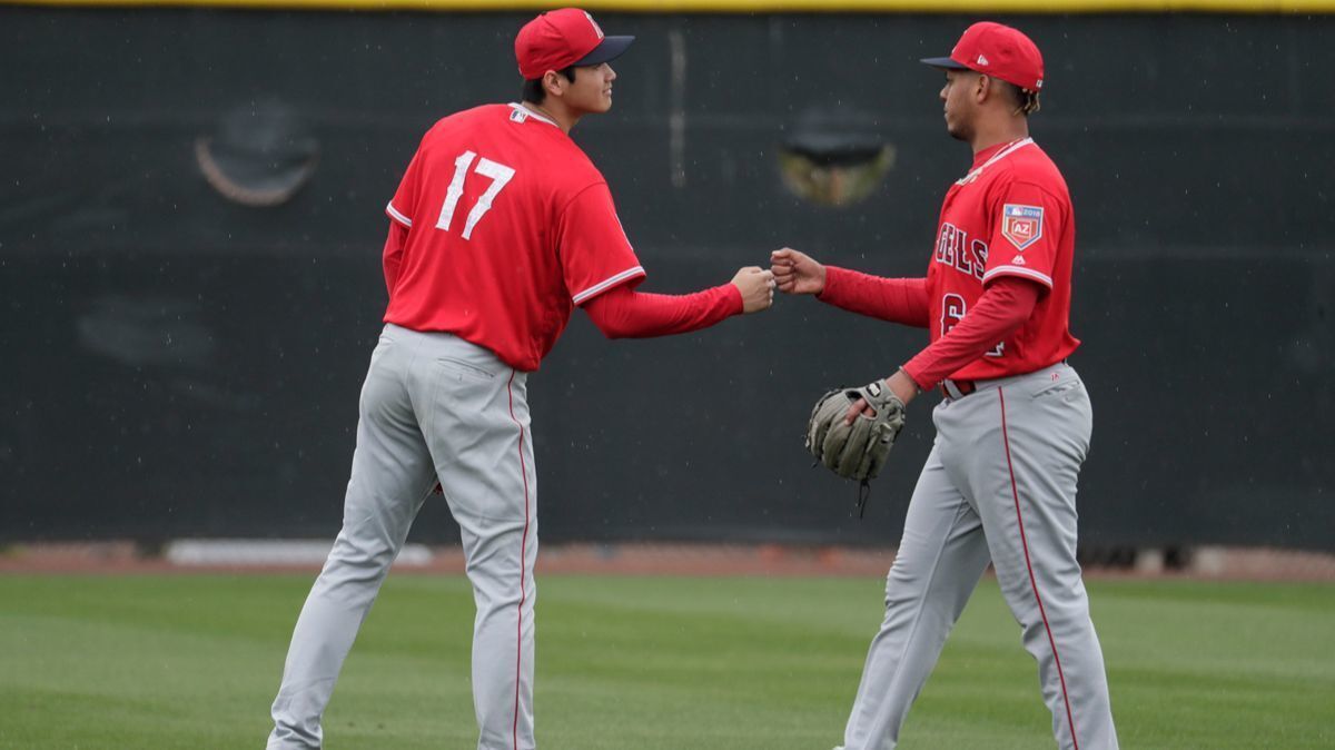 Angels teammates Shohei Ohtani, left, and pitcher Felix Pena, bump fists after playing catch at the Tempe Diablo Stadium complex on Wednesday in Tempe, Ariz.