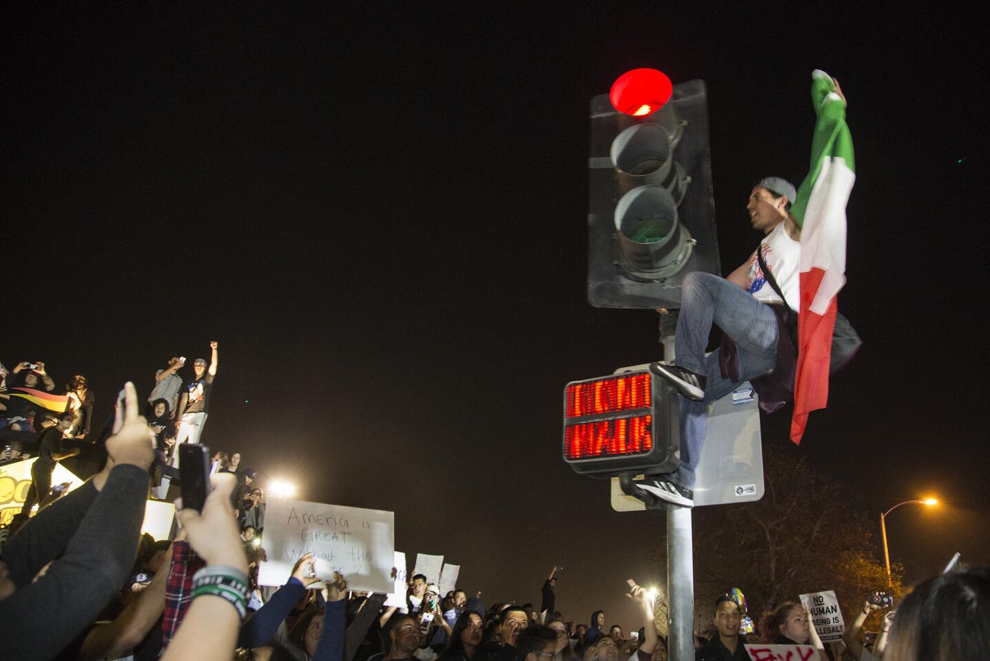 A Donald Trump protester swings from a traffic light post over the intersection of Fair Drive and Fairview Road as protesters take over the intersection near the Orange County Fairgrounds on Thursday in Costa Mesa.