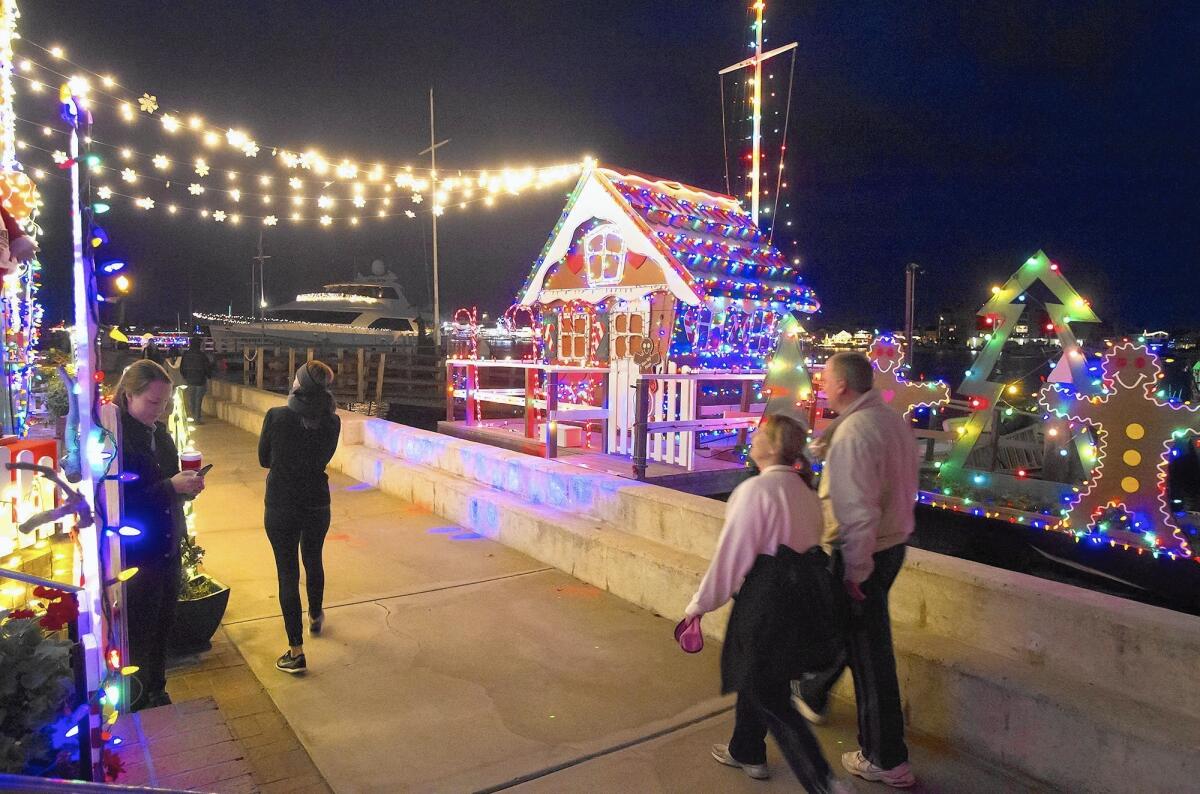 People look at the gingerbread house and accompanying winter scene that lights a home on South Bay Front on Balboa Island as part of this year's Ring of Lights event in Newport Harbor.