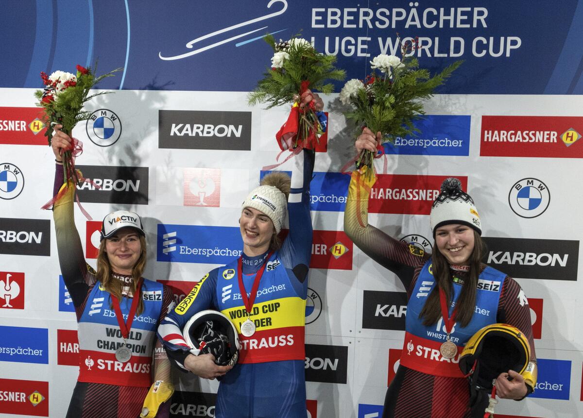 Gold medalist Madeleine Egle, center, of Austria, shares the podium with silver medalist Julia Taubitz, left, of Germany, and bronze medalist Merle Fraebel, right, also of Germany, during the luge World Cup in Whistler, British Columbia, Friday, Dec. 9, 2022. (Jonathan Hayward/The Canadian Press via AP)