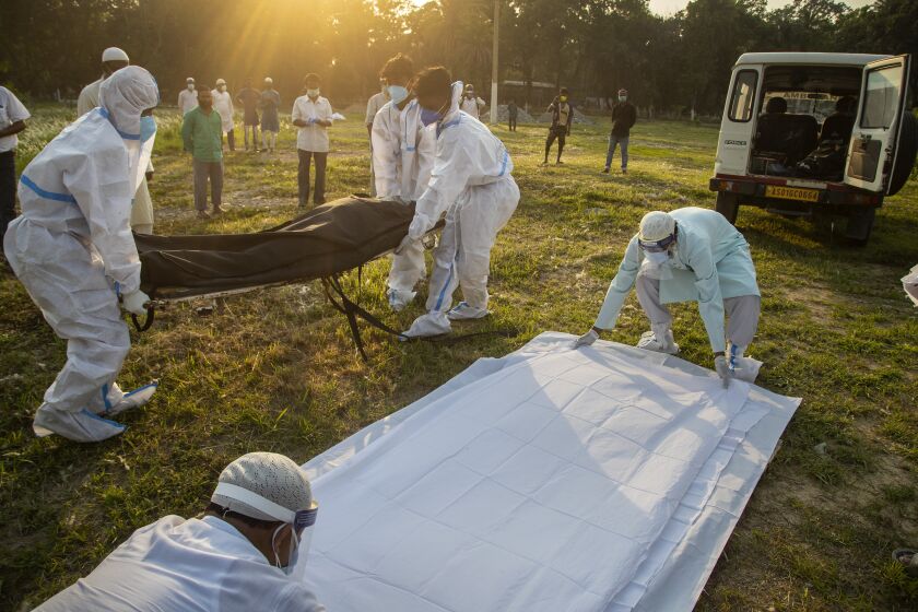 Municipal workers prepare to bury the body of a person who died of COVID-19 in Gauhati, India, Sunday, April 25, 2021. (AP Photo/Anupam Nath)