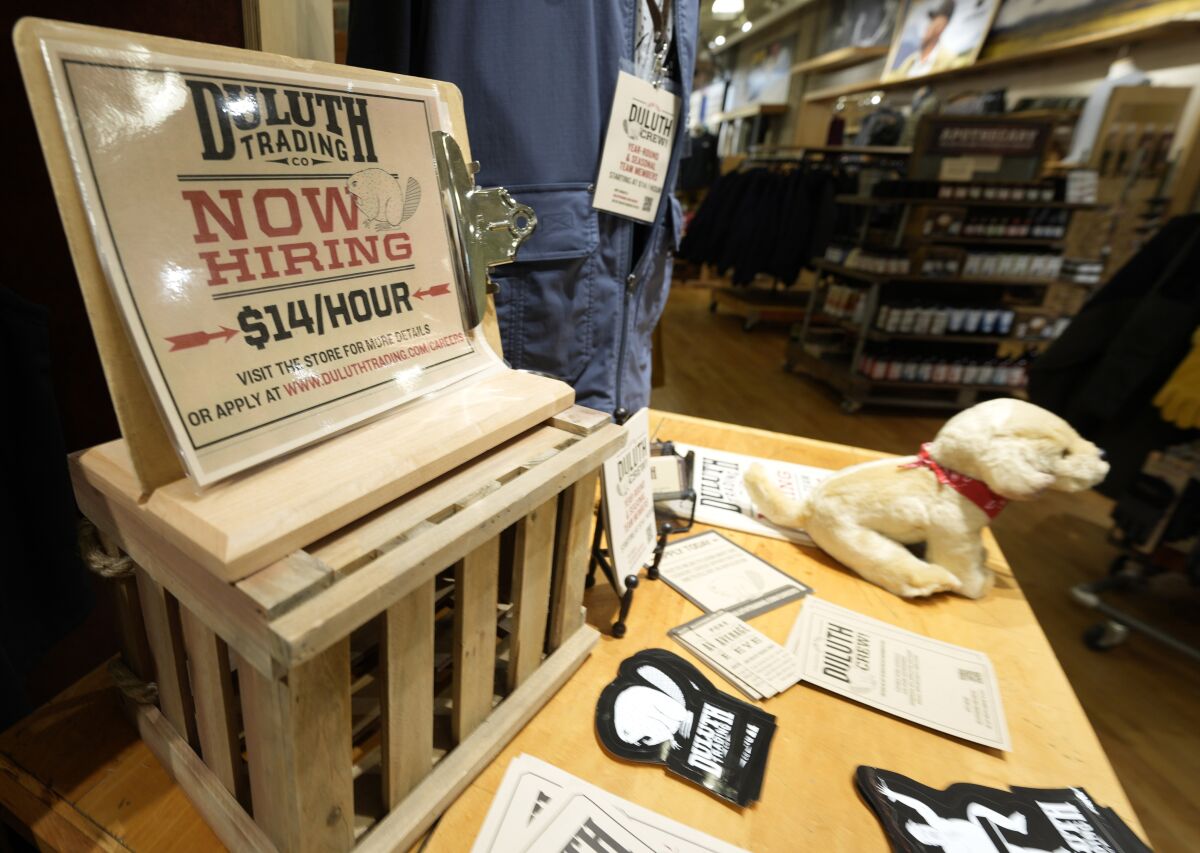 A now hiring sign sits on a display in a clothing store Saturday, Oct. 9, 2021, in Sioux Falls, S.D. The number of Americans applying for unemployment benefits fell to its lowest level since the pandemic began, a sign the job market is still improving even as hiring has slowed in the past two months. (AP Photo/David Zalubowski)