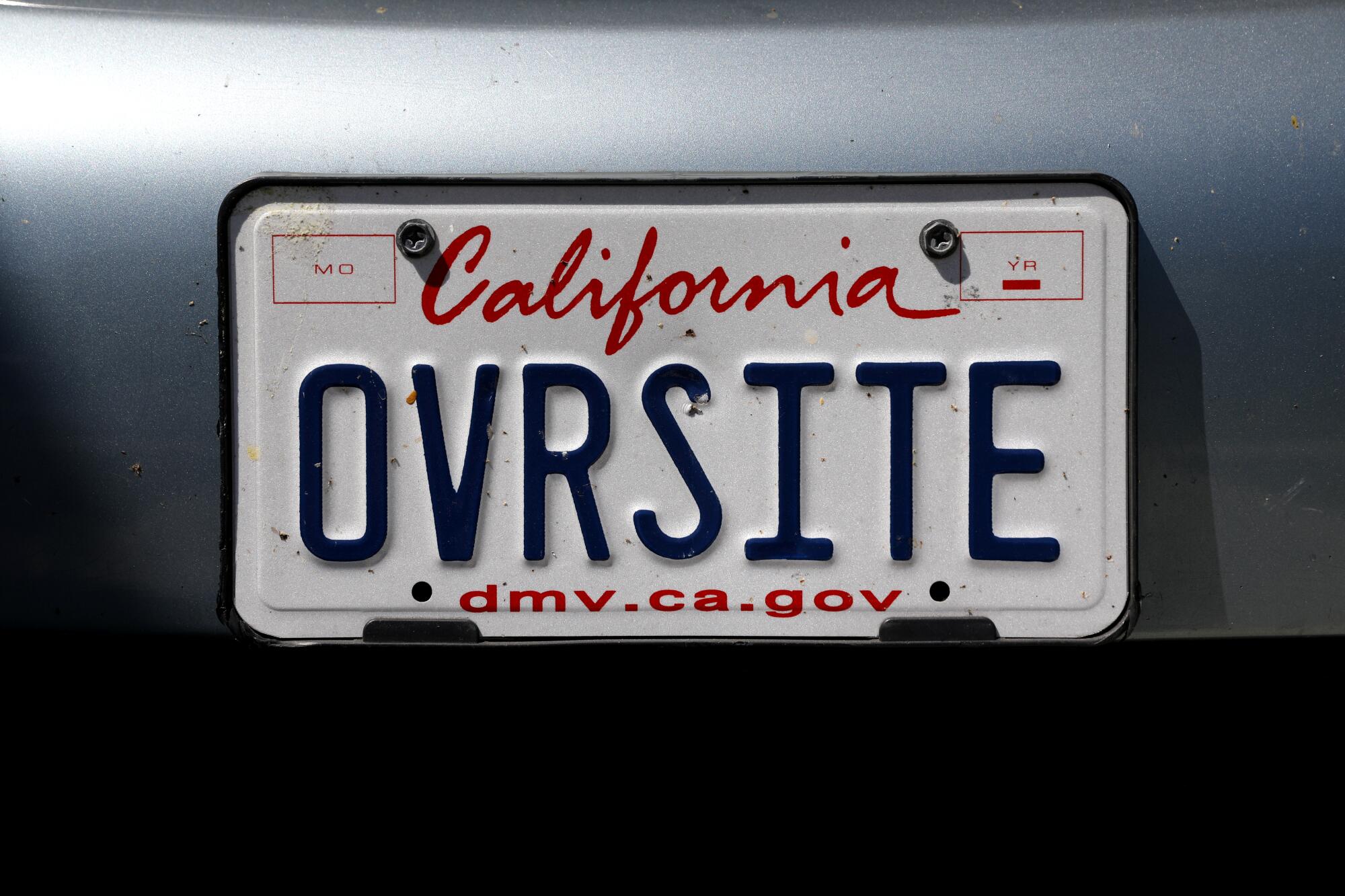 A California license plate reading "OVRSITE" on a dark vehicle