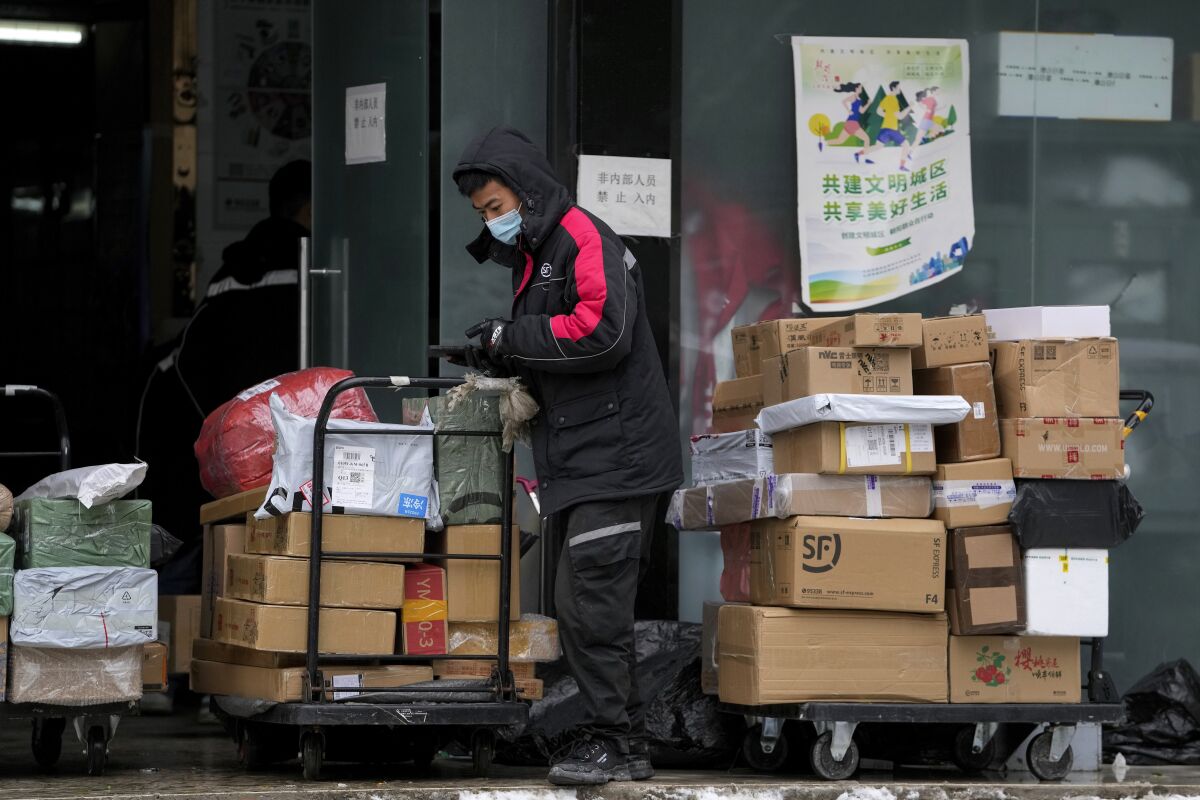 A worker of a private delivery company, wearing a face mask, sorts out parcels at its distribution center in Beijing, Sunday, Nov. 7, 2021. China's exports remained strong in October, a positive sign for an economy trying to weather power shortages and COVID-19 outbreaks. (AP Photo/Andy Wong)
