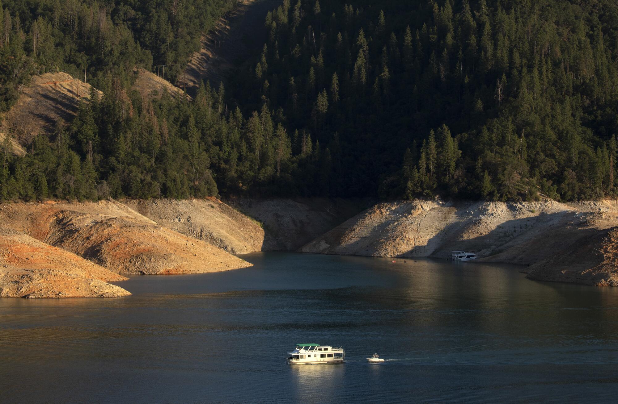 A houseboat is framed by deep bathtub rings from years-long drought at Shasta Lake in California.