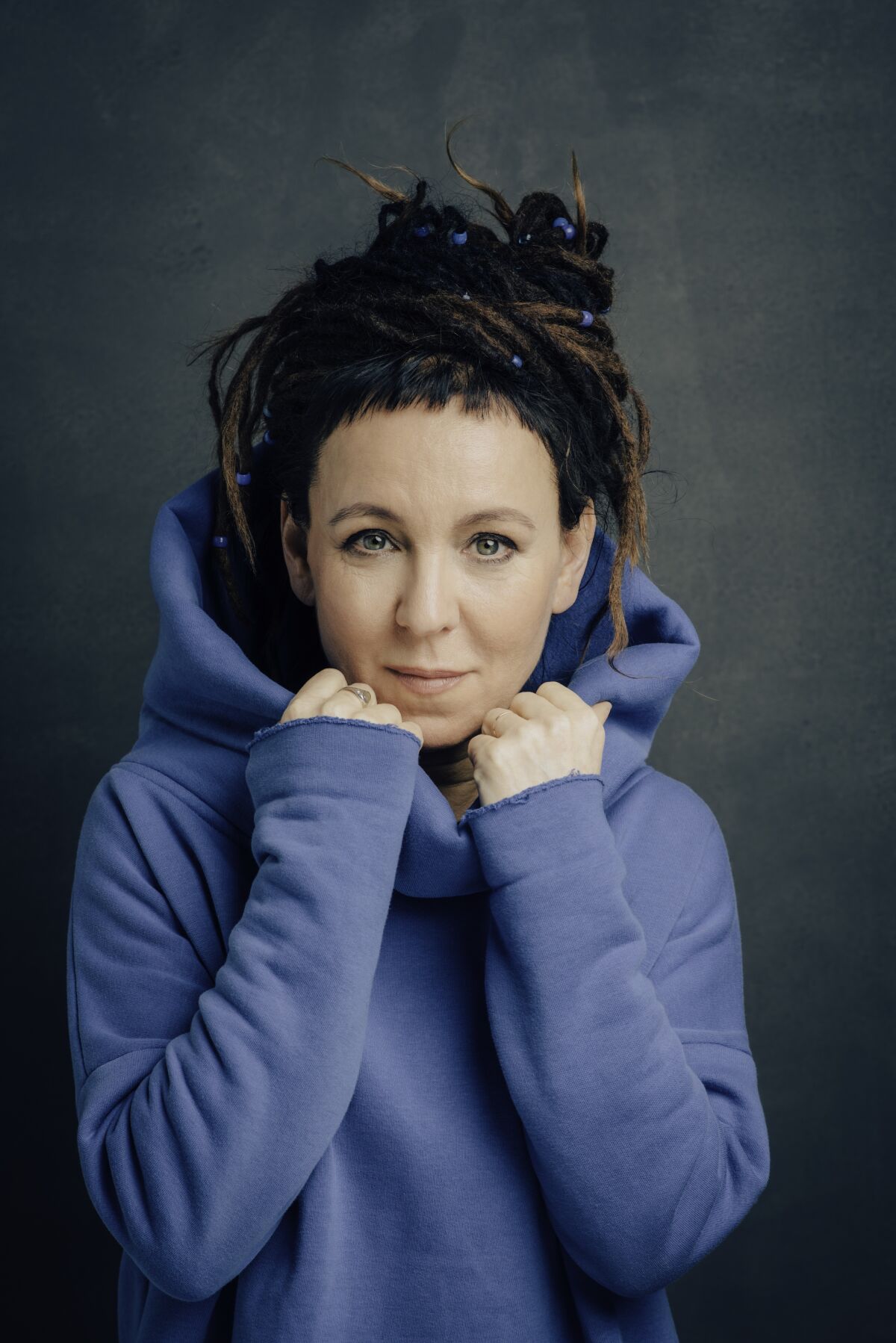 A woman wearing a purple hoodie poses