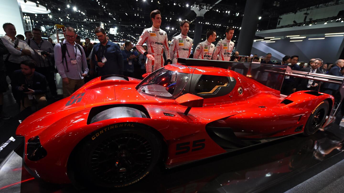 Racing team members unveils the Mazda RT24-P DPi challenger racing car at the L.A. Auto Show.