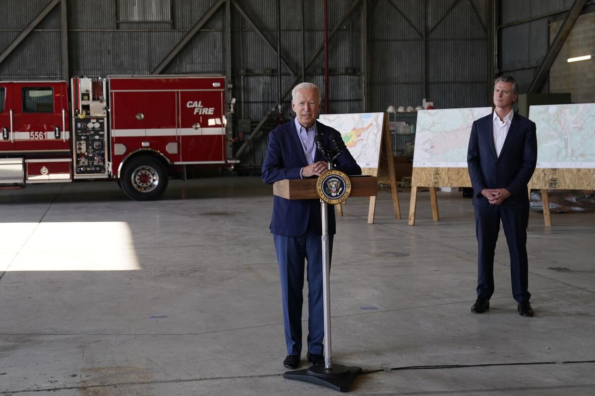 President Biden stands at a lectern with Gov. Gavin Newsom a few feet behind him.