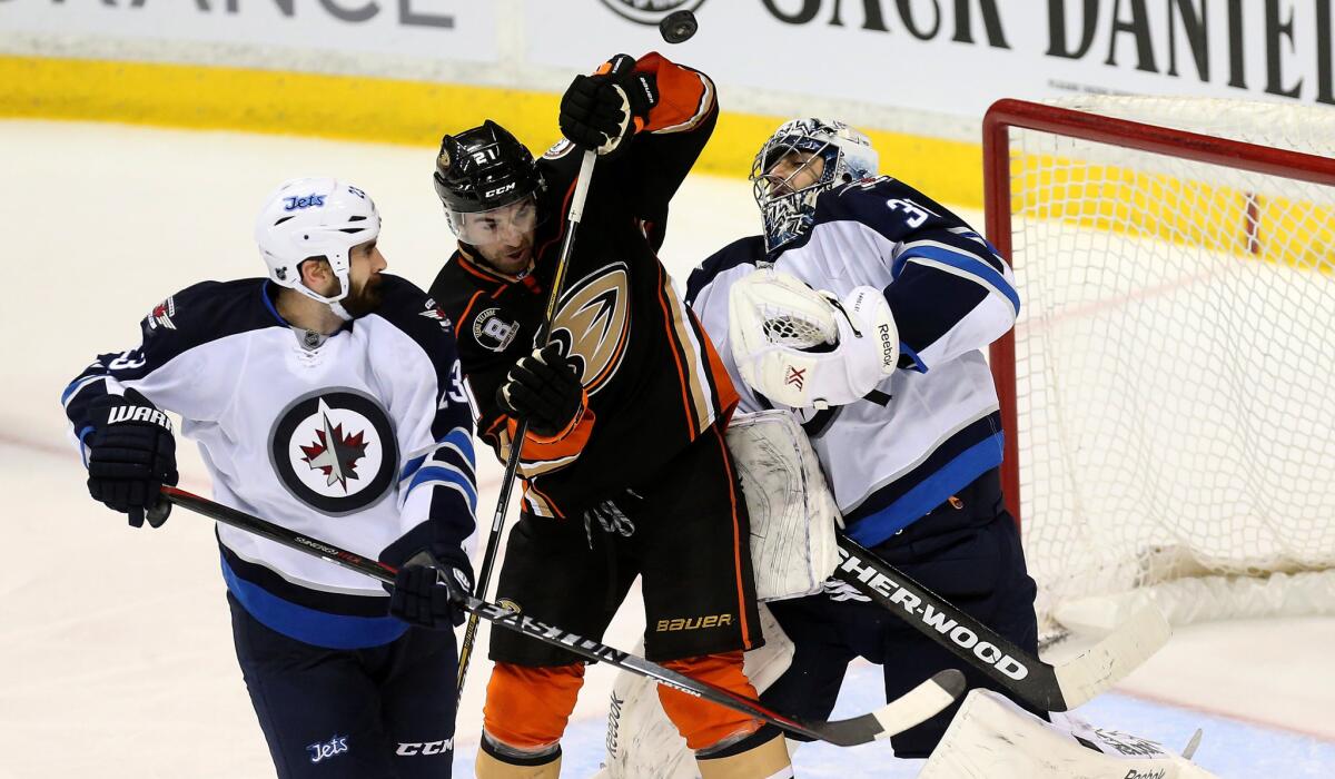 Ducks right wing Kyle Palmieri, center, tries to deflect the puck into the goal against Jets goalie Ondrej Pavelec and defenseman Jay Harrison during a game Jan. 11 in Anaheim.