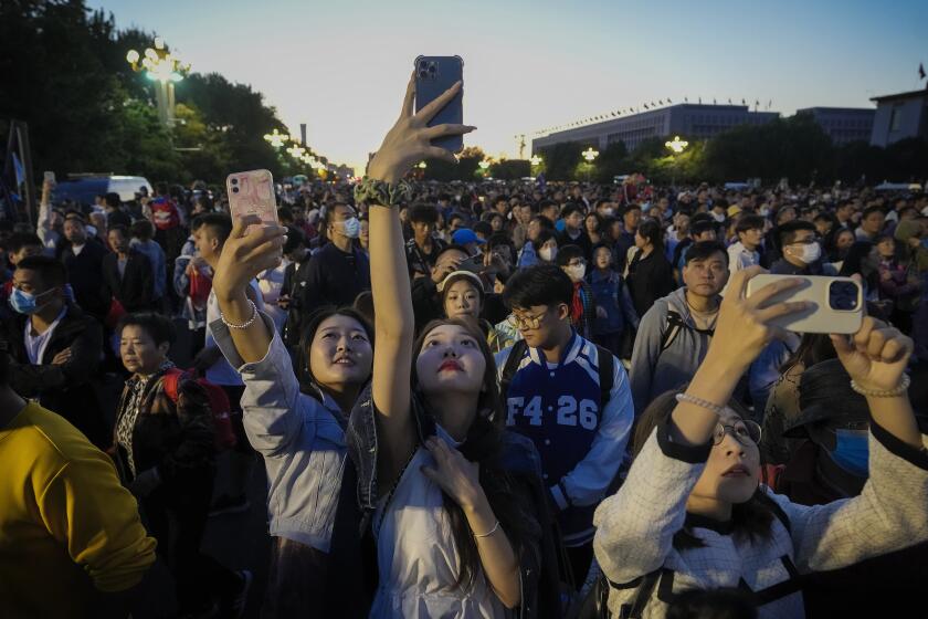 FILE - People take smartphone photos of the crowd on a street near Tiananmen Square as visitors gather to watch a flag-raising ceremony on the National Day in Beijing, Sunday, Oct. 1, 2023. The world’s population is expected to grow by more than 2 billion people in the next decades and peak in the 2080s at around 10.3 billion, a new report by the United Nations said Thursday July 11, 2024. (AP Photo/Andy Wong, File)