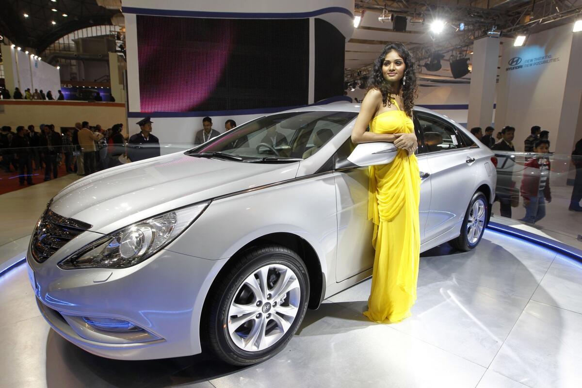 In this Jan. 6, 2012 file photo, a model poses near the new version of Hyundai Sonata displayed at the Hyundai stall during Auto Expo in New Delhi, India. On Friday, Sept. 25, Hyundai is recalling nearly a half-million midsize cars in the U.S. to replace key engine parts because a manufacturing problem could cause them to fail.