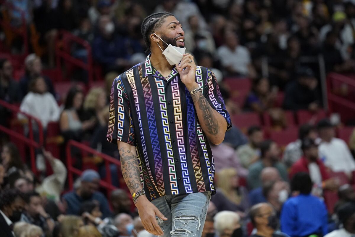 Injured Lakers forward Anthony Davis pulls down his mask as he watches the game against Miami in street clothes.
