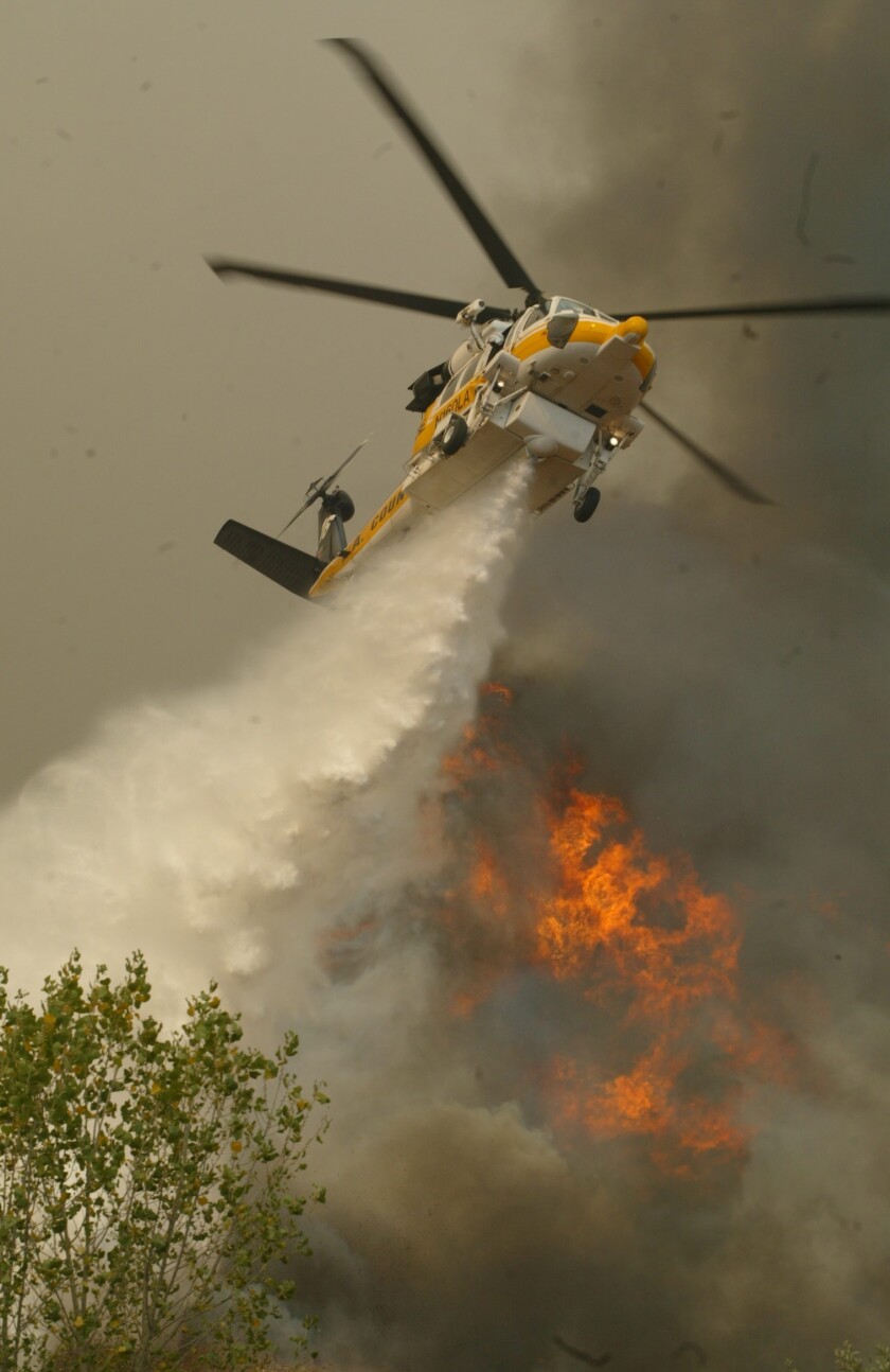 A Los Angeles County Firehawk helicopter makes a water drop on fast moving flames from the Simi Valley Fire in Towsley Canyon in Santa Clarita on Oct. 29, 2003.