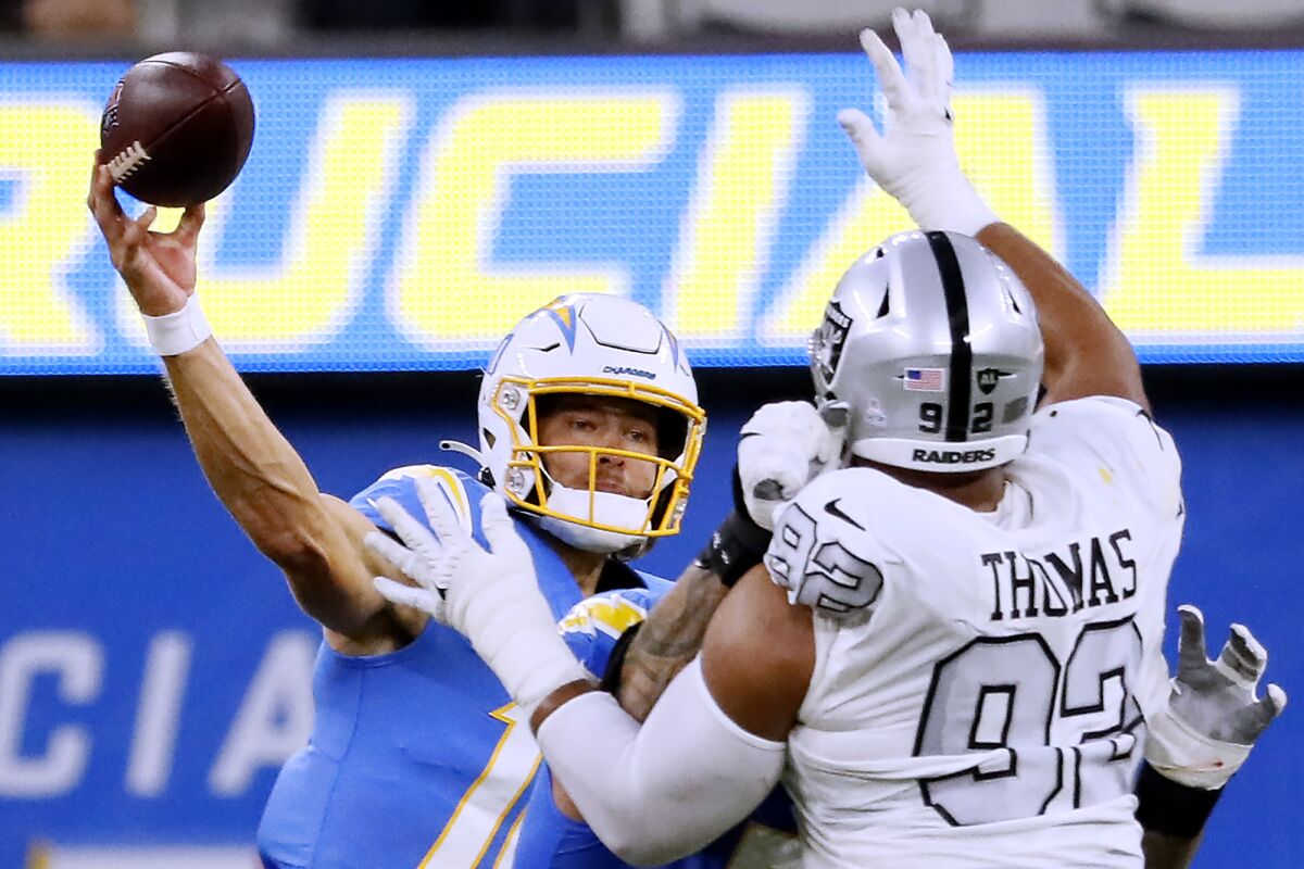 Chargers quarterback Justin Herbert attempts a pass under pressure from Las Vegas Raiders defensive end Solomon Thomas.