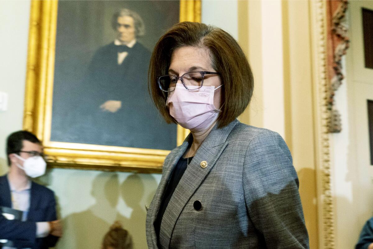 Sen. Catherine Cortez Masto walks past a portrait painting in a room