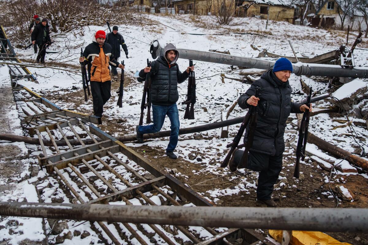 People carry rifles across a snowy landscape