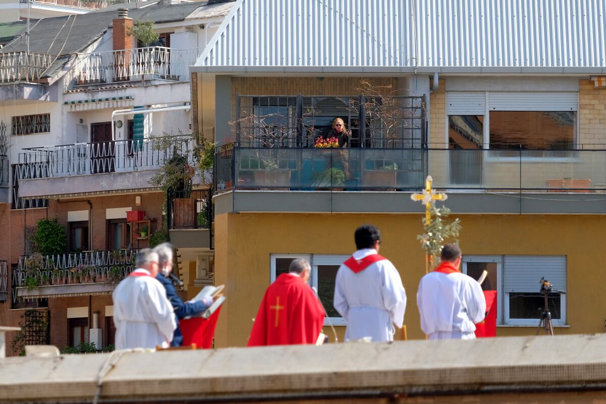 A person on a balcony follows the celebration of Palm Sunday Mass on the roof of the church of San Pio X in Rome on Sunday.