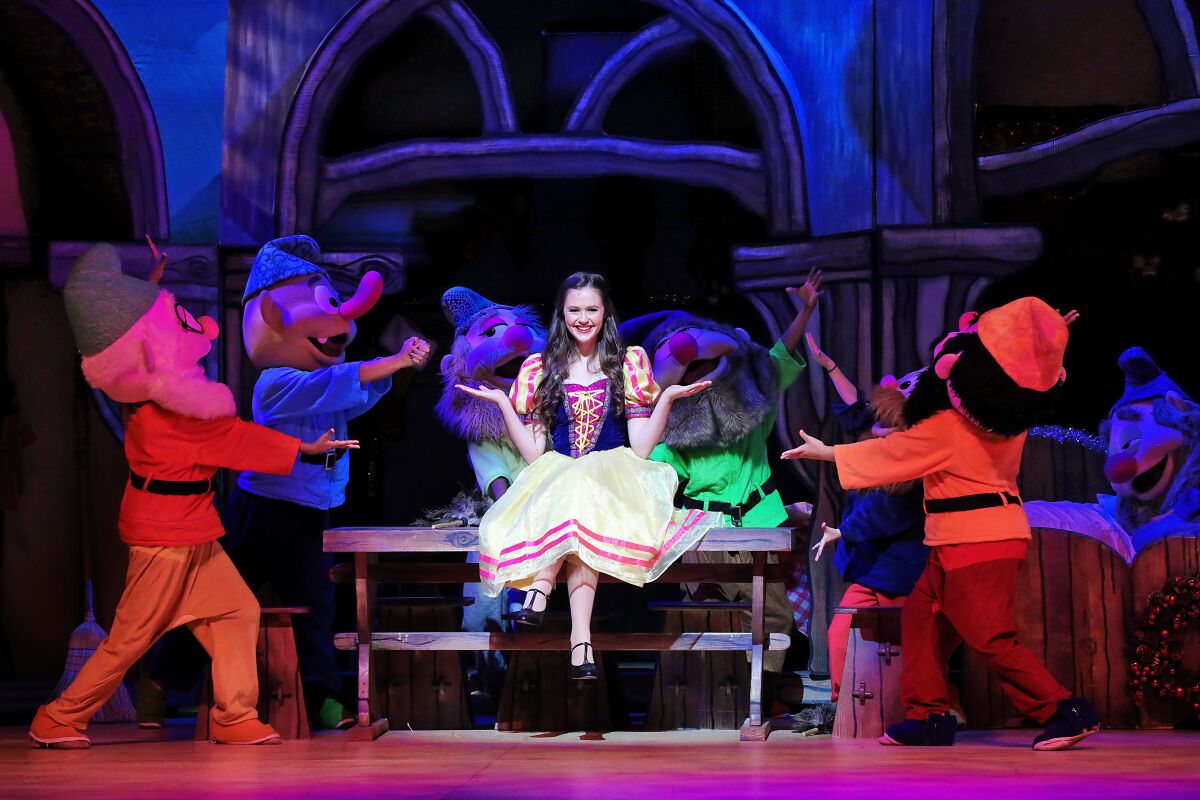 Olivia Sanabia in the lead role in "A Snow White Christmas," surrounded by people in dwarf costumes.