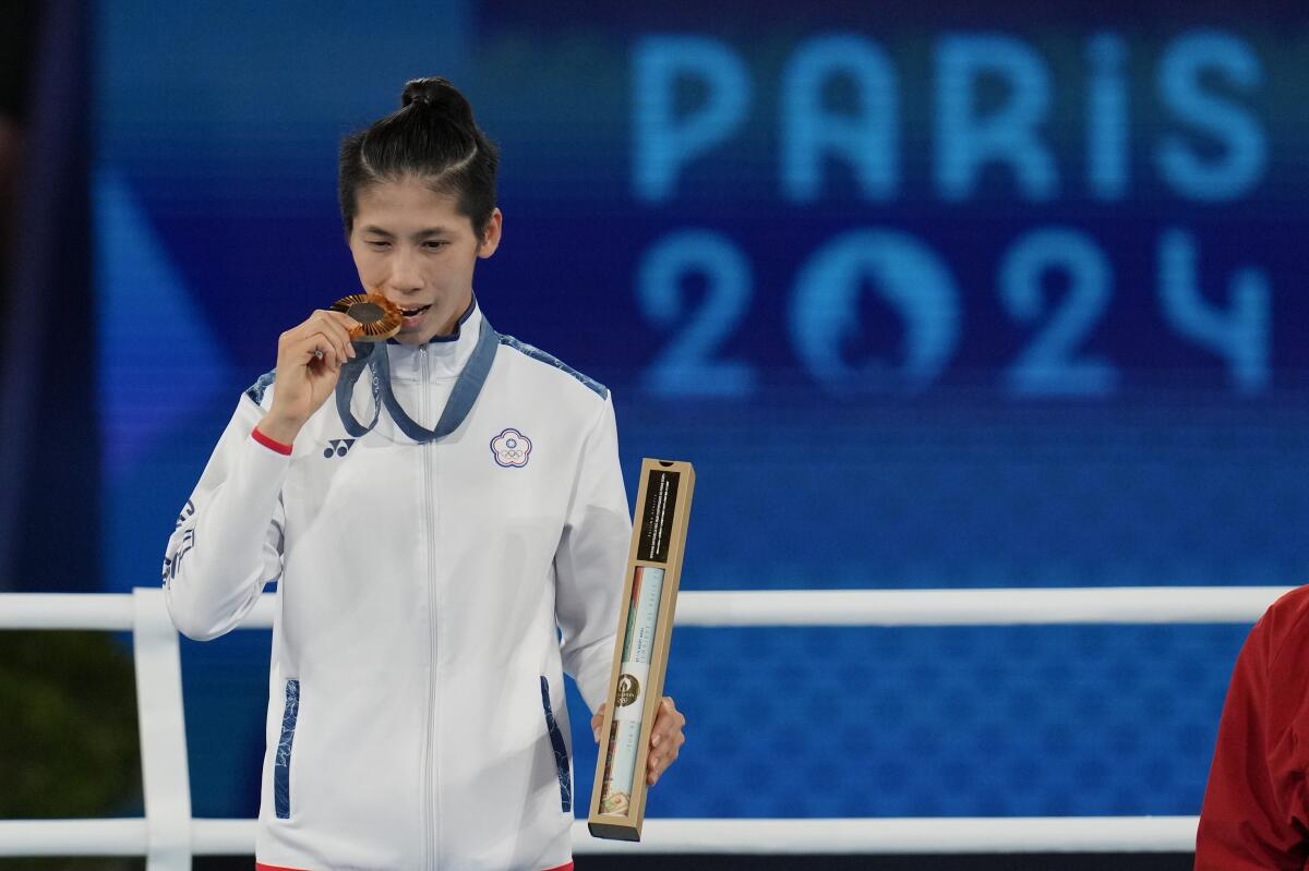 Gold medalist Taiwan's Lin Yu-ting bites her gold medal during the ceremony following the women's 57 kg final 