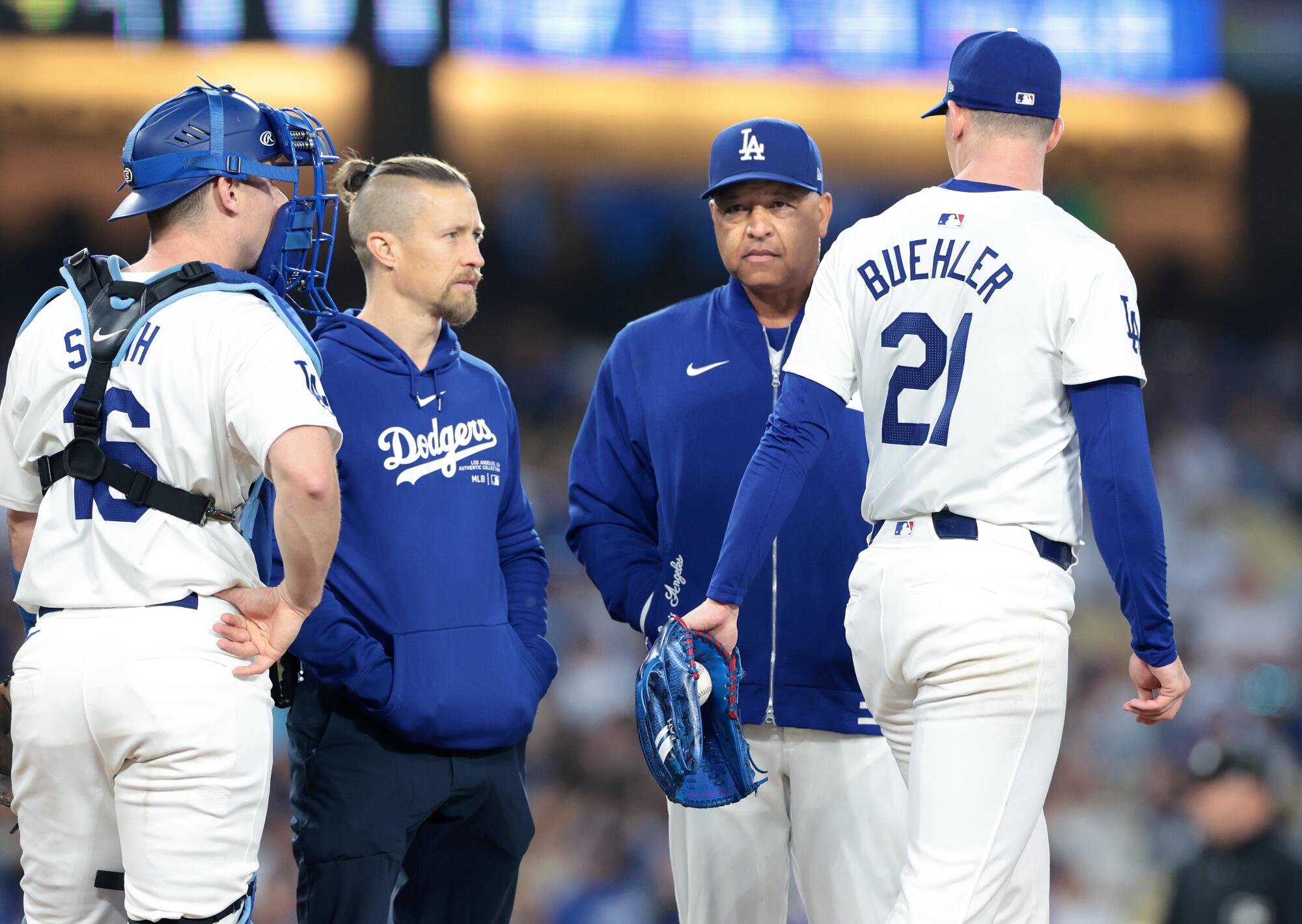 Dodgers manager Dave Roberts and a medical staff member talk with pitcher Walker Buehler as he walks off the mound