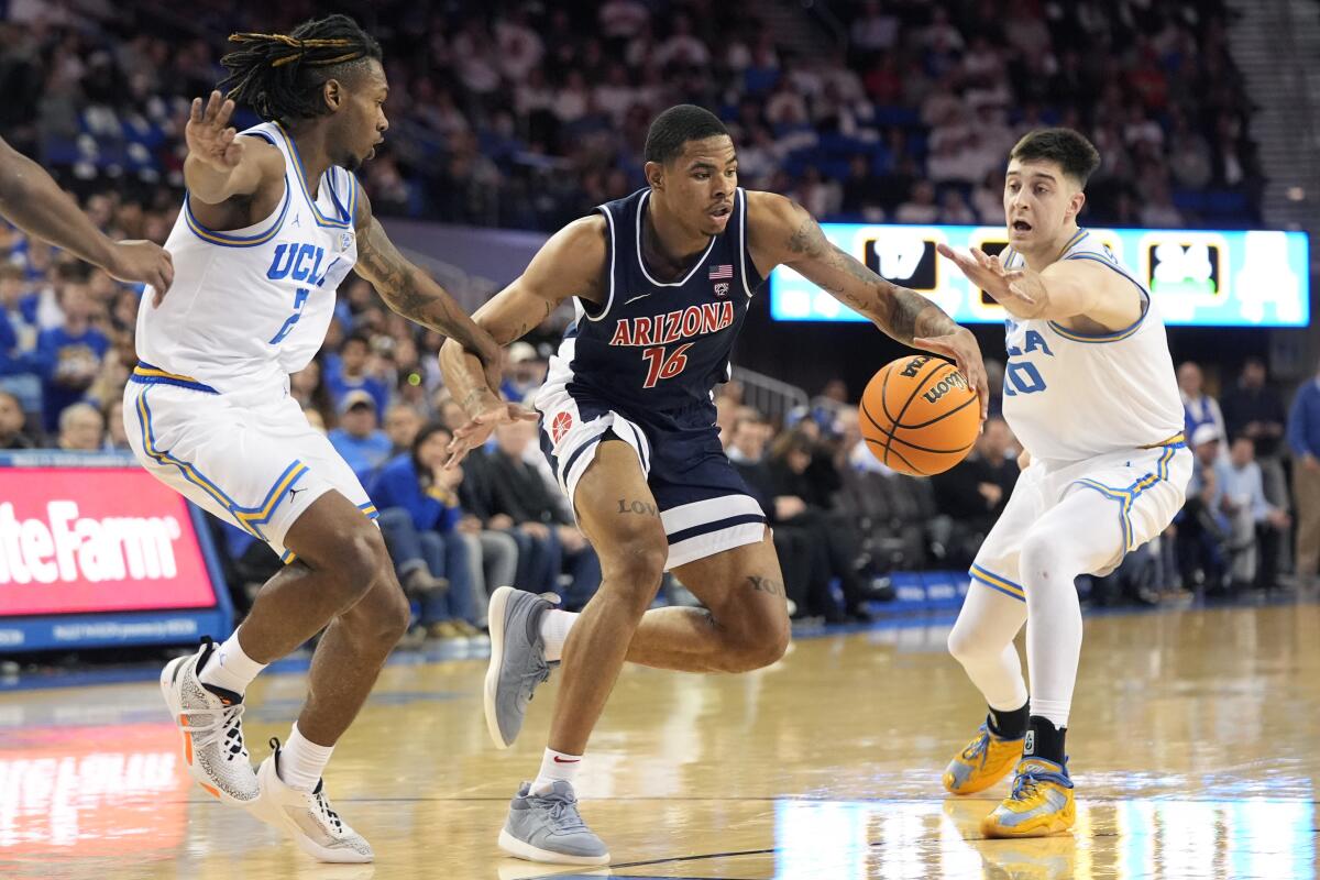 Arizona's Keshad Johnson is pressured by UCLA's Dylan Andrews and Lazar Stefanovic.