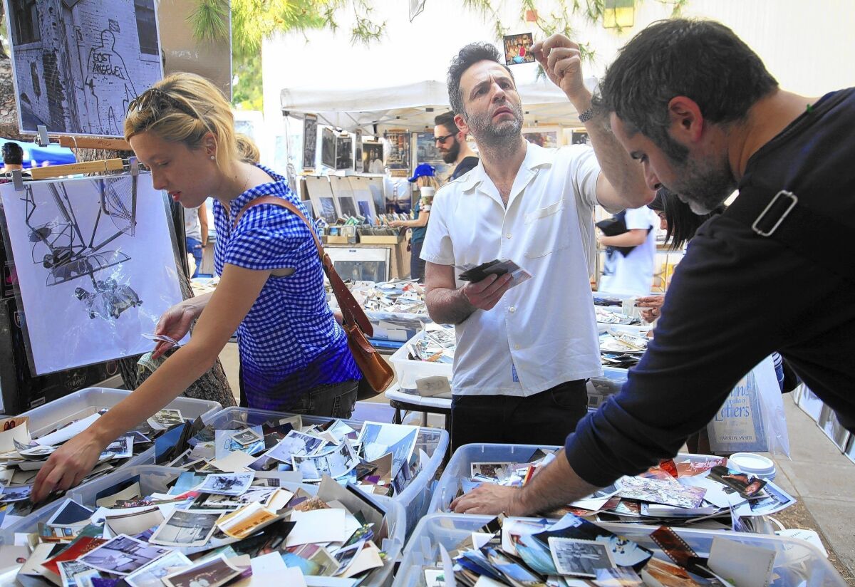 An eclectic aassortment of items awaits visitors to the Melrose Trading Post at Fairfax High School. The flea market includes artwork, glass and, for intrigued shoppers like Gustavo Salmeron, center, bins full of castoff photographs.