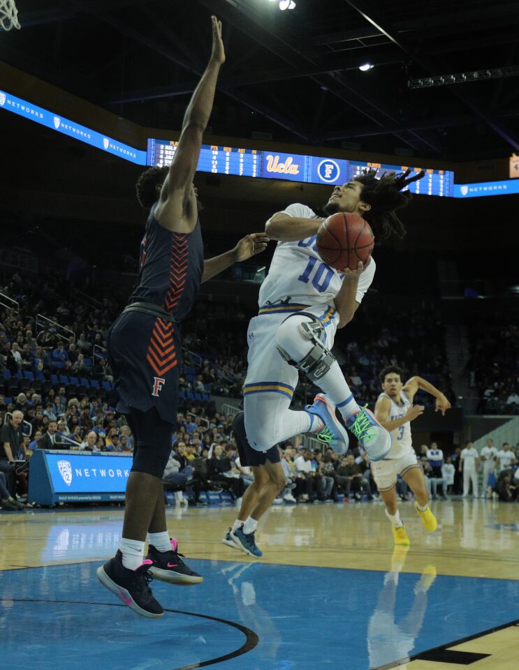 UCLA guard Tyger Campell has his drive to the basket challenged by Fullerton guard Brandon Kamga during the second half.