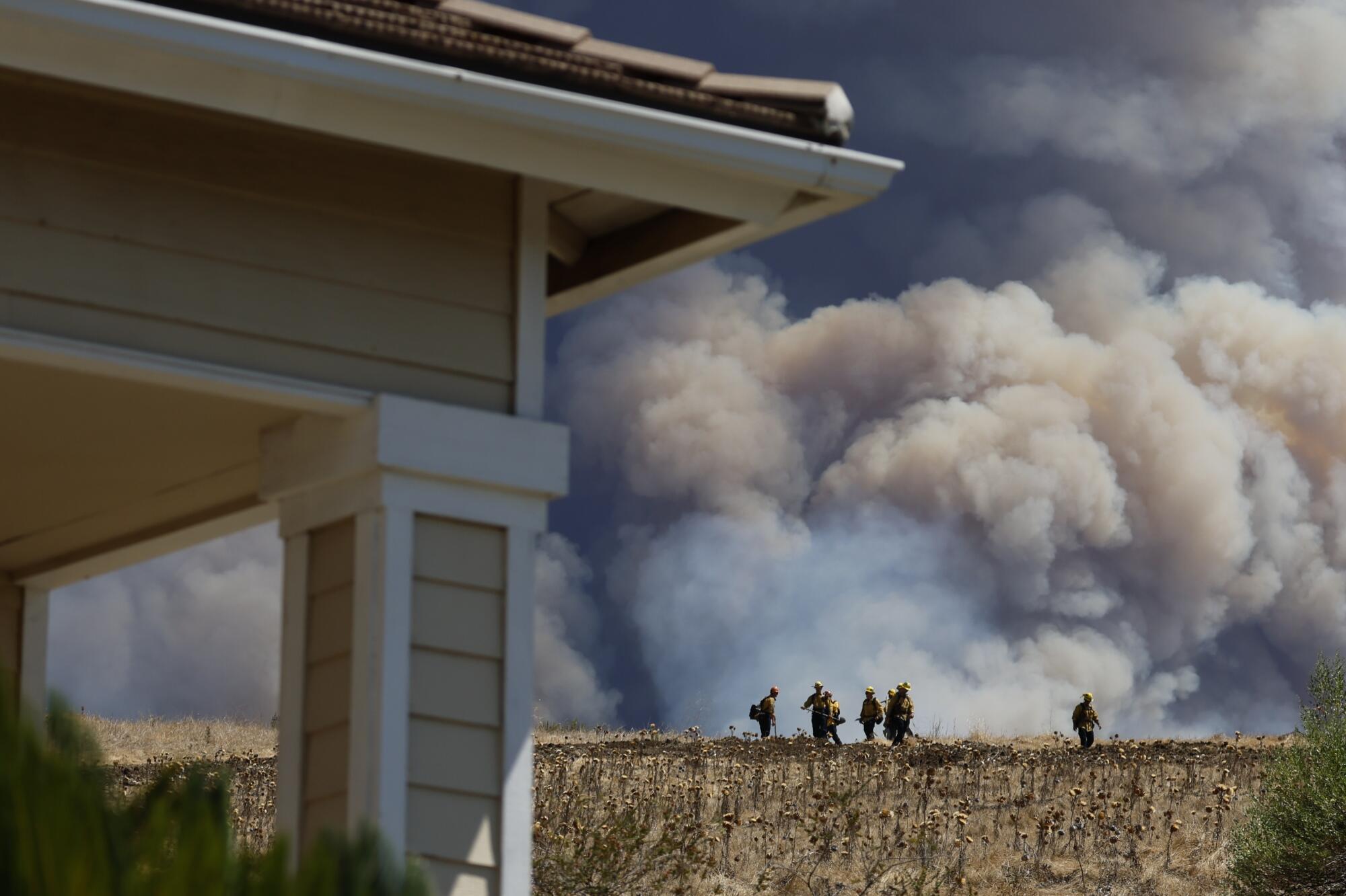 Fire crews keep an eye on the Airport fire in Ranch Santa Margarita on Tuesday. The fire has charred more than 9,000 acres.