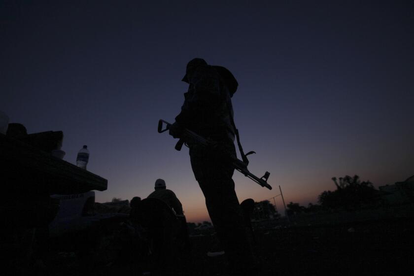 A member of a self-defense group stands at the entrance to the Mexican city of Apatzingan in February. Prosecutors announced Wednesday that the city's mayor, Uriel Chavez Mendoza, was detained on suspicion of demanding extortion payments on behalf of the Knights Templar gang.