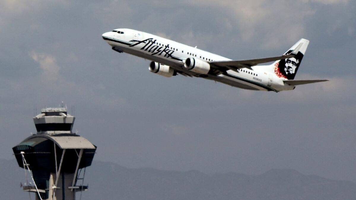 This Sept. 7, 2014 photo shows an Alaska Airlines plane taking off past the flight control tower from Los Angeles airport in Los Angeles.