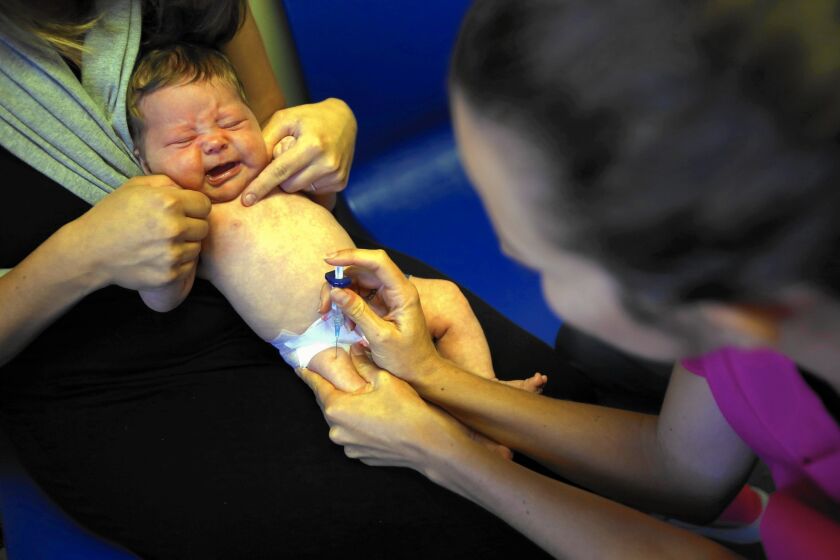 Caitlin Canelli administers a shot to 2-month-old Olive McCaffrey of Santa Monica. The number of California parents refusing to vaccinate their kindergartners dropped slightly in 2014.