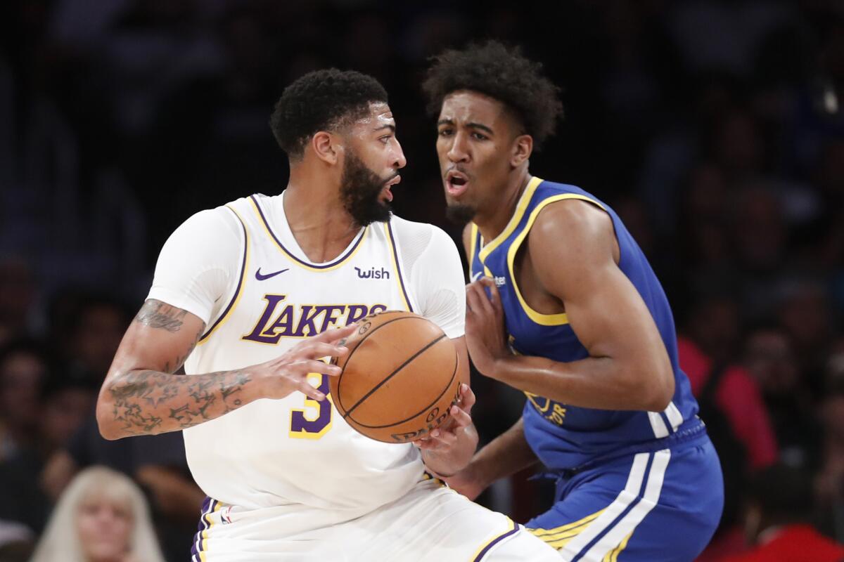 Laker Anthony Davis drives to the basket against the Warriors' Kavion Pippen 