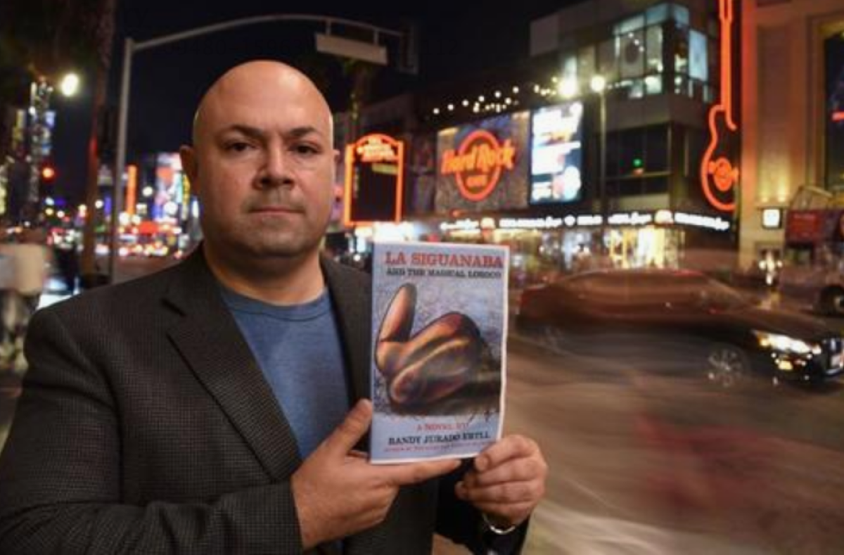 El escritor Randy Jurado Ertll posa para Efe mostrando la portada de su libro "La Siguanaba and the Magical Loroco" el 10 de noviembre en Hollywood, California. EFE/Iván Mejía