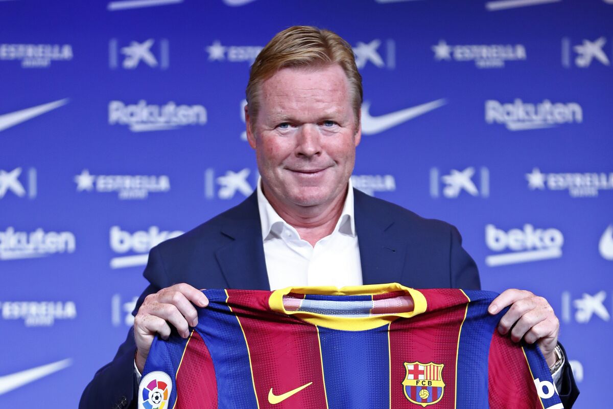 Ronald Koeman holds up a Barcelona soccer shirt during his official presentation as coach for FC Barcelona in Barcelona, Spain, Wednesday, Aug. 19, 2020. Barcelona officially announced earlier on Wednesday a deal with Koeman to become their coach five days after the team's humiliating 8-2 loss to Bayern Munich in the Champions League quarterfinals. Barcelona says the former defender's deal runs through June 2022. Koeman replaces the fired Quique Setien. (AP Photo/Joan Monfort)