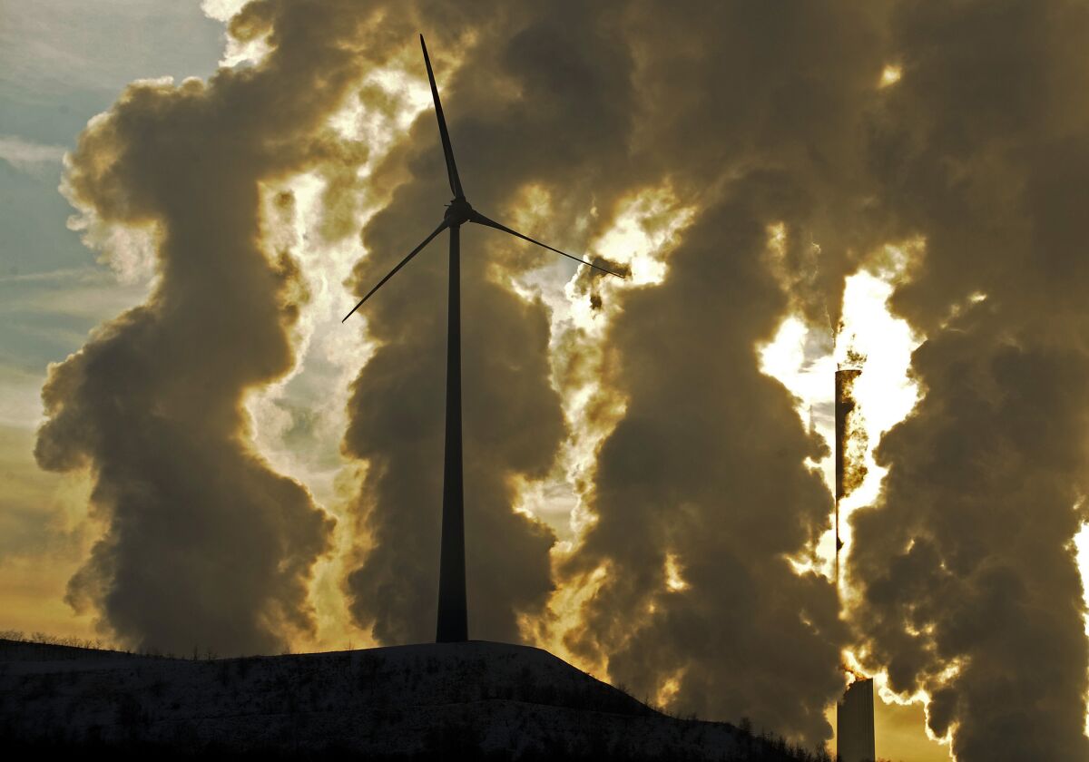 A wind turbine stands in front of a coal-fueled power plant in Gelsenkirchen, Germany, in December 2010.
