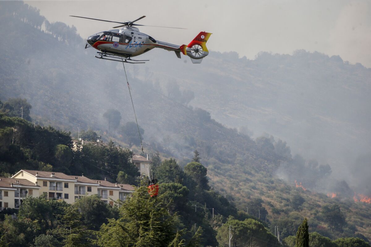 Emergency staff fights a fire on Castillo mountain park near Tivoli a few miles from Rome, Italy, Friday, Aug. 13, 2021. Intense heat baking Italy pushed northward towards the popular tourist destination of Florence Friday while wildfires charred the country's south, and Spain appeared headed for an all-time record high temperature as a heat wave kept southern Europe in a fiery hold. (Cecilia Fabiano/LaPresse via AP)