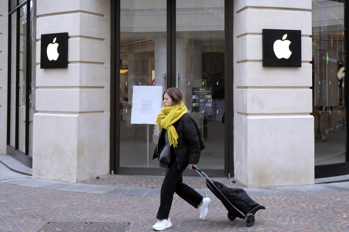 FILE - A woman walks past a closed Apple Store in Lille, northern France, Monday, March 16, 2020. A French watchdog ordered Apple to withdraw the iPhone 12 from the market because it is emitting too high levels of electromagnetic radiation. The National Frequencies Agency (ANFR), the body monitoring public exposure to radiations, called on Apple to "implement all available means to rapidly fix this malfunction," in a statement released on Tuesday Sept.12, 2023. (AP Photo/Michel Spingler, File)