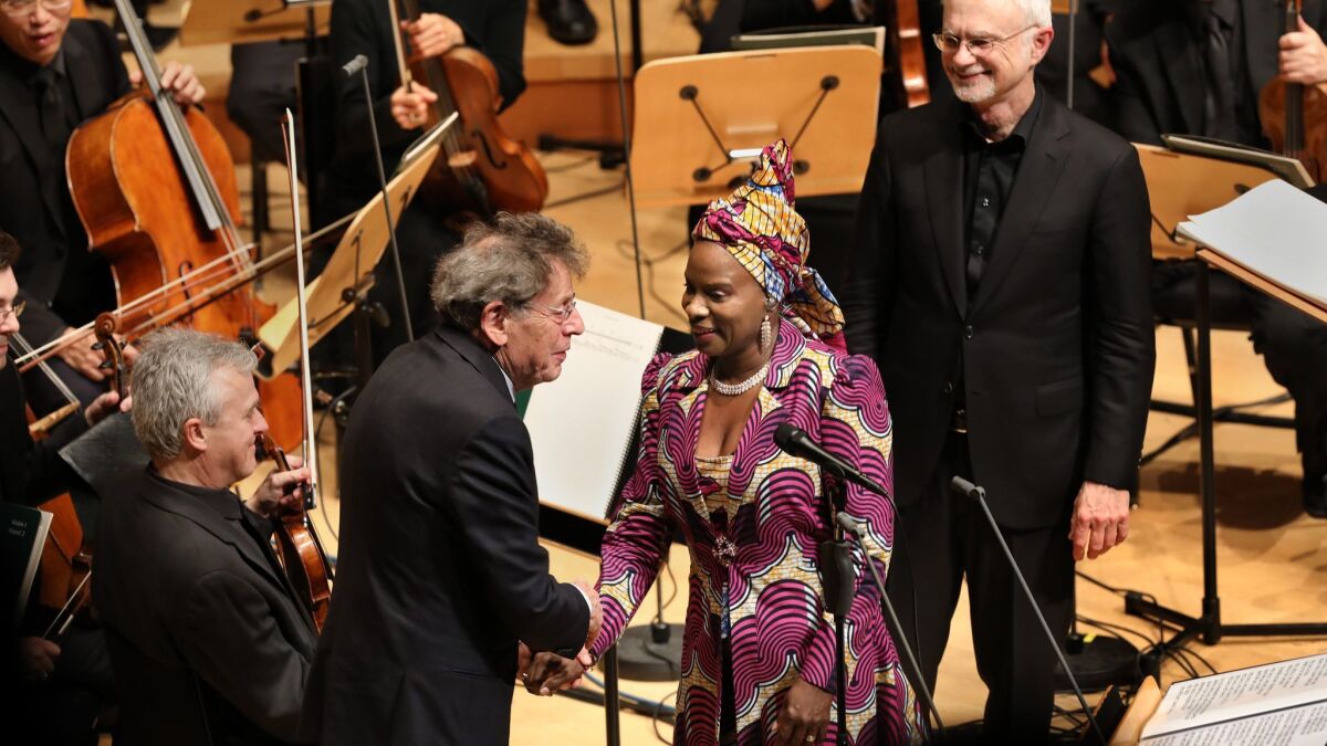 Composer Philip Glass shakes hands with singer Angèlique Kidjo as John Adams looks on Thursday night at the world premiere of Glass' Symphony No. 12.