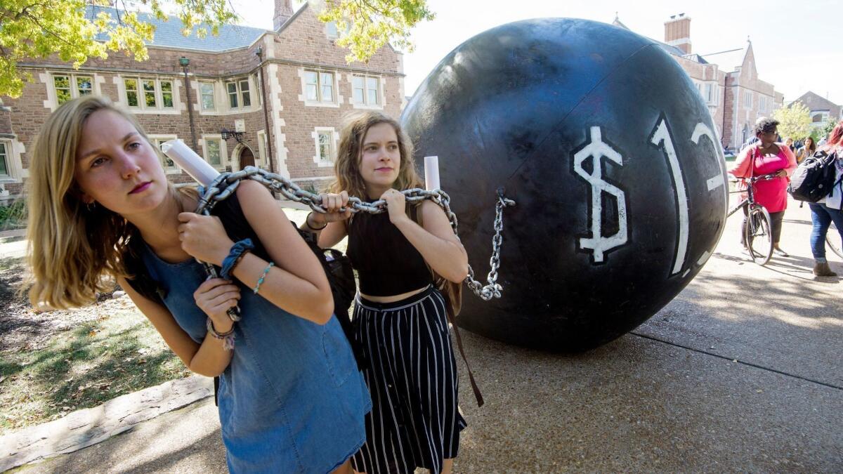 Students pull a ball and chain representing the $1.4 trillion in outstanding student debt at Washington University in St. Louis. More than 100 companies put some money toward employees’ student loans, according to the Society for Human Resources Management.