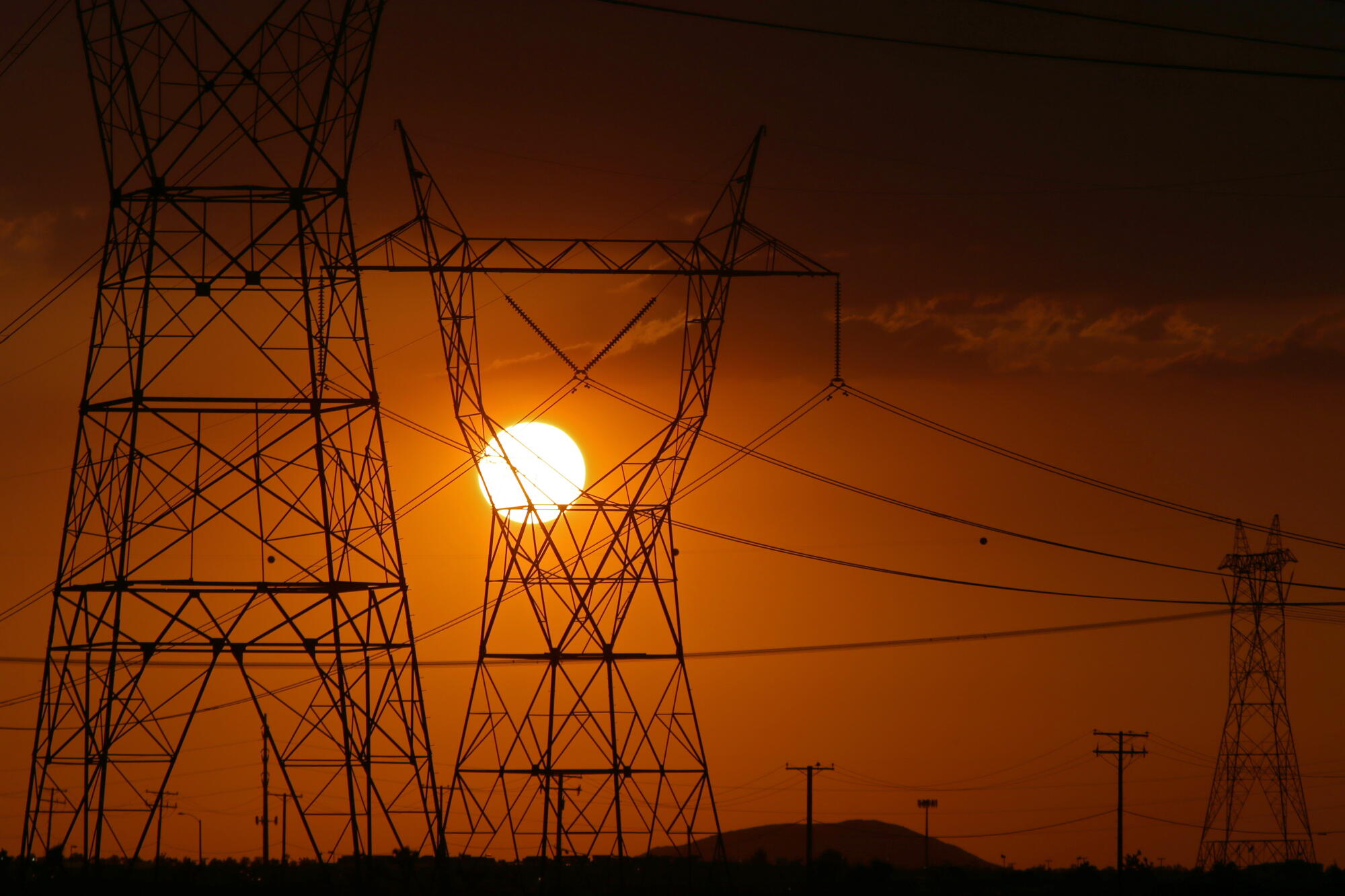 The sun sets behind power lines in the city of Adelanto, Calif.