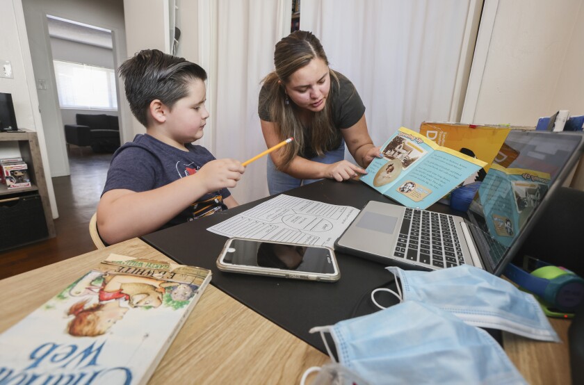 Geo Gillam, 8, works on school work with is mother, Edith Carmona, at their home in San Diego Friday.